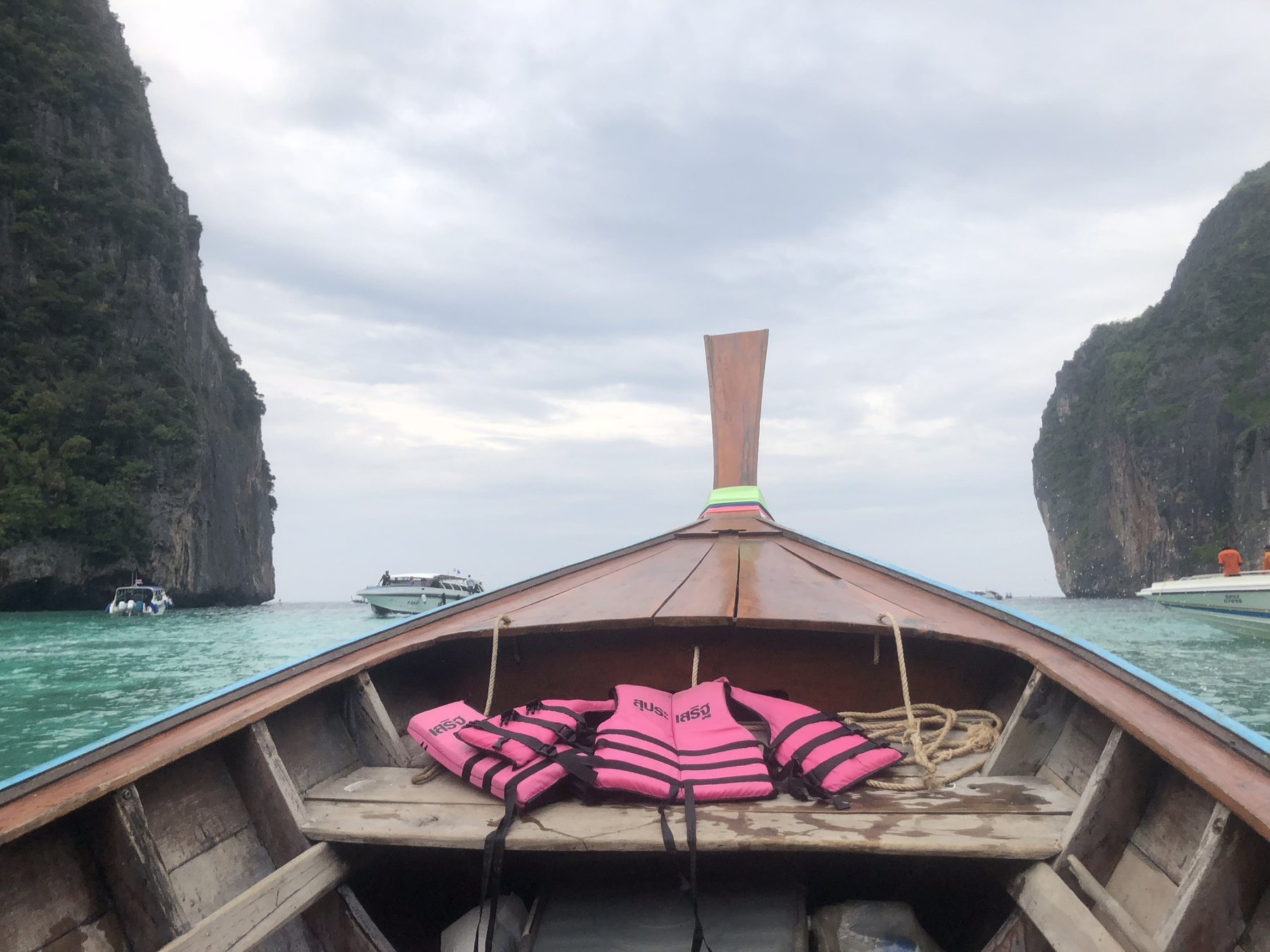 Phi Phi Islands — The classic long-tail view: bow pointing toward a wall of limestone.