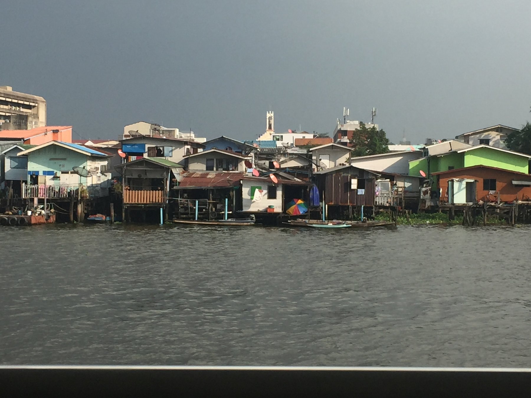 Bangkok — Life along the Chao Phraya — waterside homes seen from the river.
